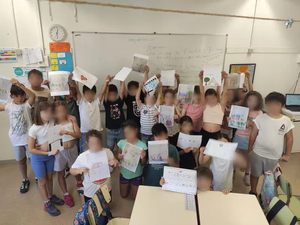 El alumnado de la Escola El Palau levanta en el aula las cartas recibidas desde la Amazonia, con las caras difuminadas