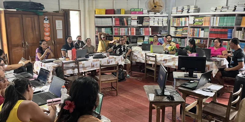 La biblioteca de la Escola Ixubãy Rabuī Puyanawa llena de docentes trabajando con ordenadores portátiles durante la formación