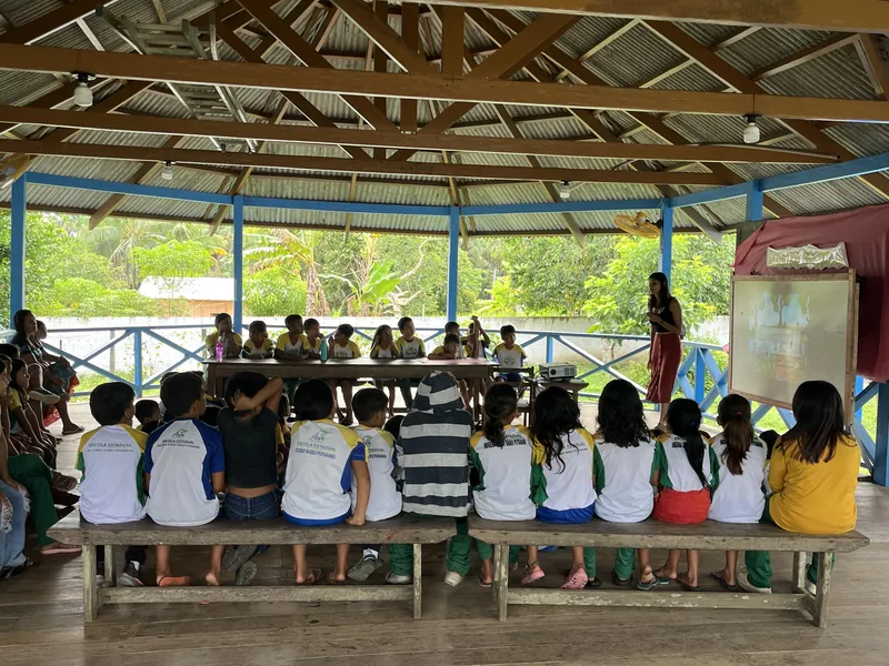 Alumnado de la Escola Ixubãy sentado de espaldas en el aula abierta durante un taller de sostenibilidad