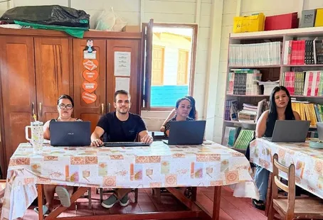 El profesor Jonas Anjos y tres educadoras con portátiles en una mesa del aula de la Escola Ixubãy Rabuī Puyanawa