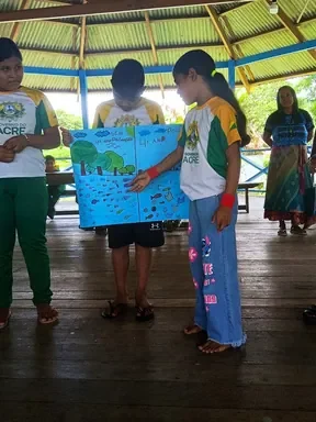 Dos estudiantes de la Escola Ixubãy presentan un cartel con el río dibujado durante el taller, con las caras difuminadas