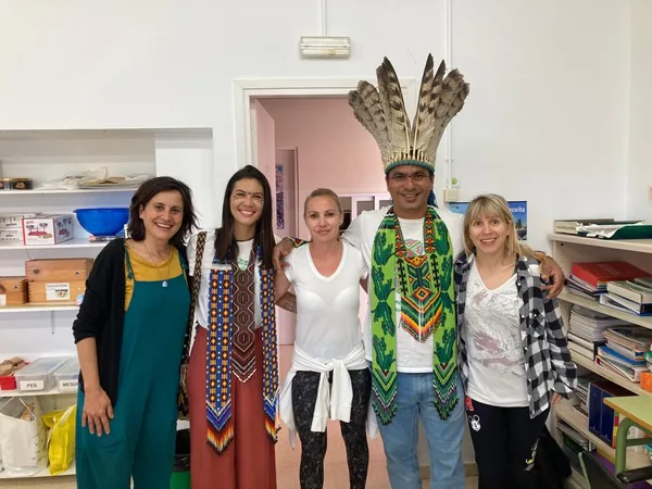 Puwê Puyanawa, con corona de plumas, y su hija Txuku con el equipo de maestras de la Escola Guillem de Claramunt en un aula