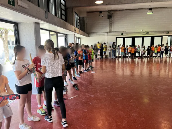 El alumnado de la Escola Guillem de Claramunt espera en el gimnasio, con las flautas en la mano, para recibir a Puwê y Txuku Puyanawa; caras difuminadas