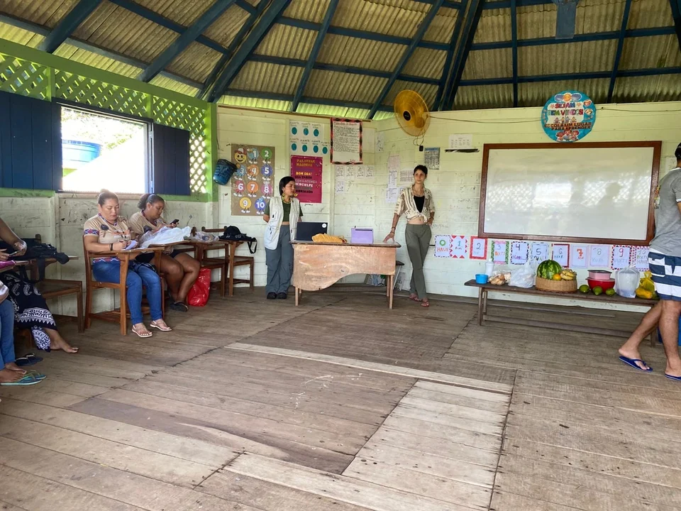 Un aula de la Escola Pedro Antônio de Oliveira con los pupitres de madera, los trabajos en la pared y una educadora de pie junto a la pizarra