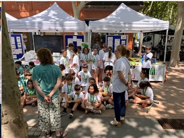 El alumnado de 5.º A de la Escola Sant Cristòfor, con las camisetas de su cooperativa escolar, en la parada solidaria de la Rambla de Begues; caras difuminadas